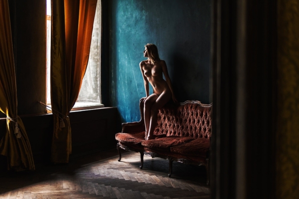 Niche, a figure on a red velvet sofa beside a window