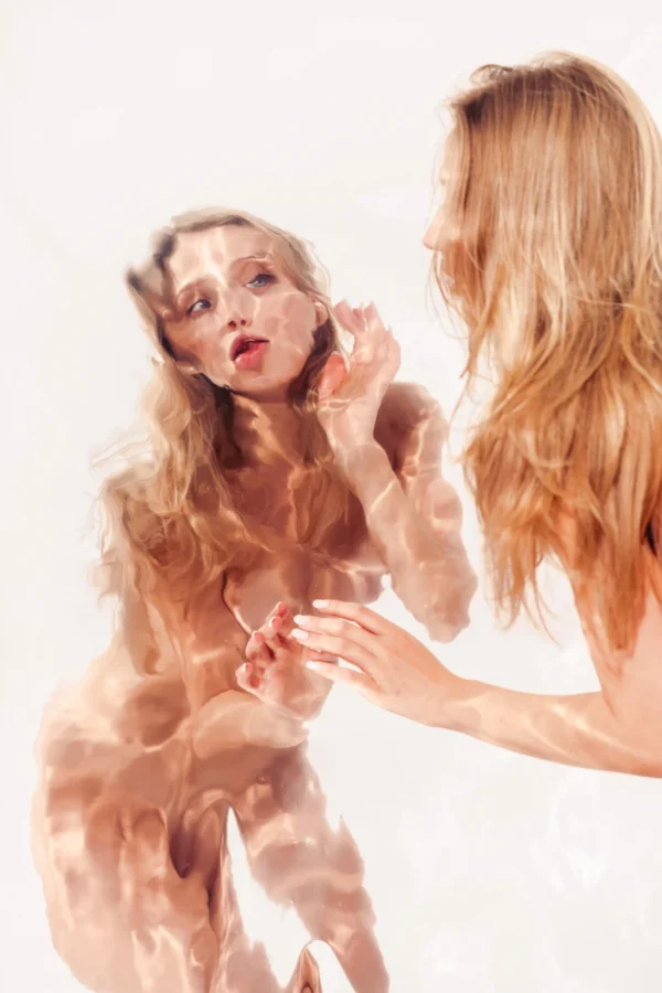 Dysmorphia, a woman facing her warped reflection in a bent mirror sheet